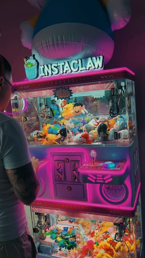 Neon-lit Instaclaw claw machines filled with plush prizes